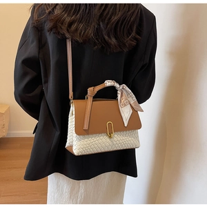 Detail of a chic two-tone handbag with a brown leather flap and woven white body