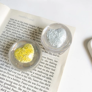 Gros plan de supports de téléphone en résine avec motifs de cœur jaune et blanc sur livre