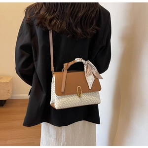 Detail of woven beige texture and brown leather flap with silk scarf handle