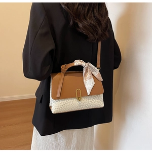 Detailed view of bicolor leather and woven handbag with gold clasp and decorative silk scarf