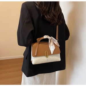 Brown leather and white woven handbag detail featuring a gold buckle and silk scarf