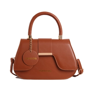 Brown leather crossbody bag with curved base and gold metal trim on the front flap
