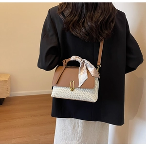 Detail view of woven contrast handbag with scarf handle on model in black suit