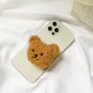 Cute brown plush teddy bear expandable phone grip stand on a white smartphone