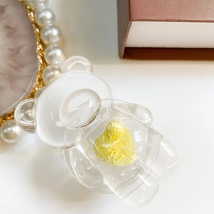 Detailed view of a transparent bear phone grip with a textured yellow heart insert