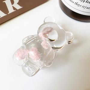 Gros plan sur une pince à cheveux ours transparente avec pompons roses sur fond blanc