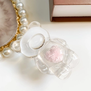 Detail shot of transparent bear phone grip with a soft pink plush heart on a tray
