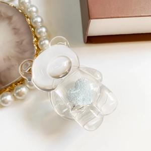 Detailed close-up of transparent bear phone grip with blue plush heart inside