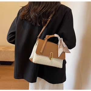 Detail of a woven contrast handbag featuring a brown leather flap and decorative silk scarf