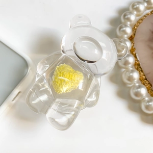 Close-up of transparent resin bear phone stand with a textured yellow heart insert