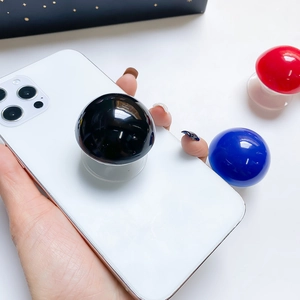 Close-up of spherical glossy phone grip in black, red, and blue on a white background