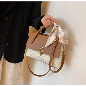 Close-up of woven handbag with leather flap, gold lock and decorative bear print silk scarf