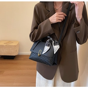 Detail of black patchwork handbag with woven texture, U-shaped buckle and silk scarf