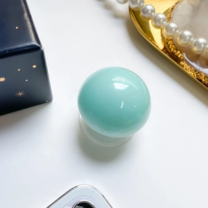 Detail of mint green crystal ball phone grip with a glossy mirror finish on white background