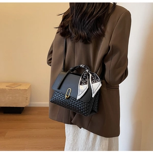 Detail of black woven shoulder bag with silk scarf handle and golden U-shaped lock