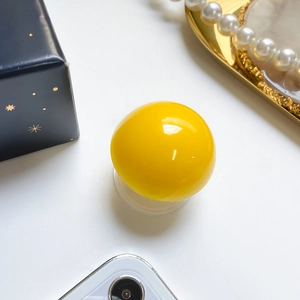 Close-up of glossy yellow spherical phone grip stand with polished resin mirror finish