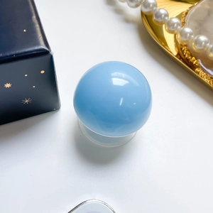 Close-up of a light blue spherical phone stand with its elegant dark blue gift packaging