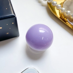 Detail of lavender crystal ball phone grip on a white surface with gift box and pearls