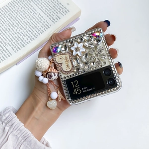 Close-up of sparkling rhinestone folding phone case with floral decor and pearl charm