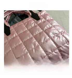 Detail showing pink quilted tote bag fabric with checkered patterns and black handles