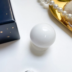 Close-up of a white sphere phone grip with suction base on a luxury jewelry tray
