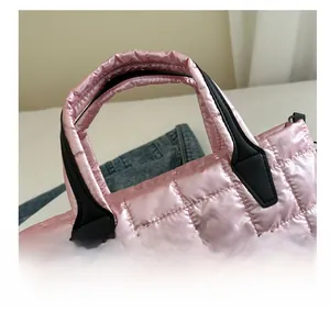 Detail of pink quilted tote bag with black handles and reinforced stitching accents