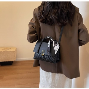 Close-up of black woven leather handbag with gold U-buckle and bear silk scarf detail