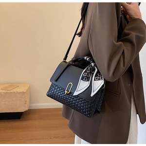 Detail of black leather and woven bag with golden clasp and floral silk scarf