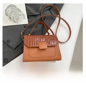 Detail of a brown textured crossbody bag showing faux crocodile pattern and smooth leather