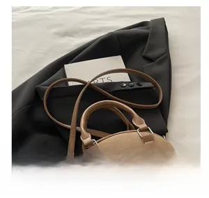 Detail showing the brown suede pillow bag with metallic rivets and slender shoulder strap