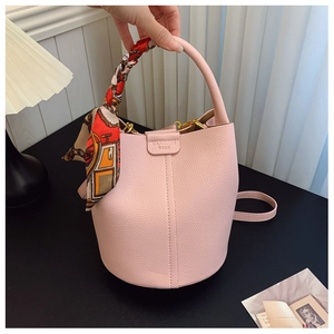 Detail of pink lychee leather bucket bag with silk scarf handle and gold hardware