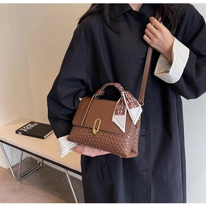 Detail of woven leather handbag with gold U-buckle and elegant silk scarf handle