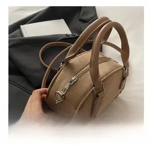 Close-up of smooth silver zipper and suede texture on caramel brown shoulder bag