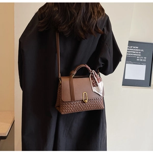 Detail of a brown vintage tote with woven texture, smooth leather, and silk scarf handle