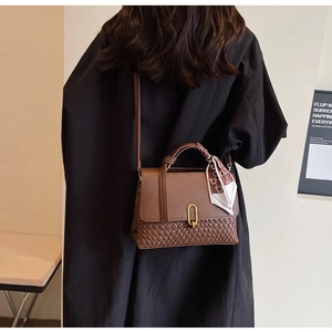 Brown leather crossbody bag featuring a woven base, gold clasp, and silk scarf handle
