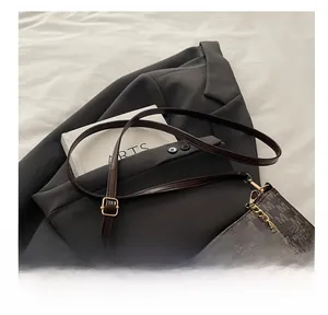 Dettaglio di borsa a spalla marrone con stampa a motivo M e catena con logo dorato