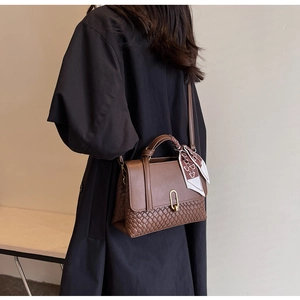 Brown handbag with woven texture detail and bear print silk scarf worn with black coat