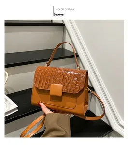 Detail of brown flap crossbody bag showing croc-embossed texture and gold metal buckle