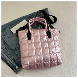 Detail of square quilted pink tote bag with black handles on denim jacket surface