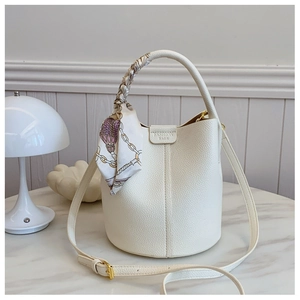 Detail of white lychee leather bucket bag with silk scarf handle and embossed logo