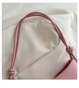 Detail of a pink handbag shoulder strap featuring a stylish knot design and soft texture