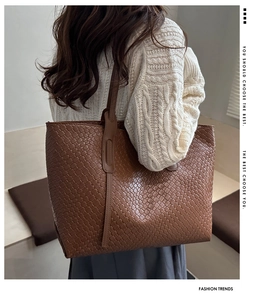 Dettaglio di una borsa tote marrone intrecciata con grande capacità e sottili spalline