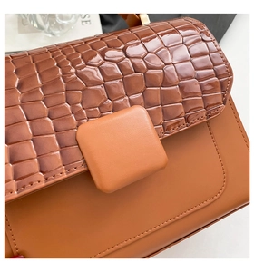 Detail der karamellbraunen Handtasche mit Krokodilprägung und quadratischer Leder-Schnalle