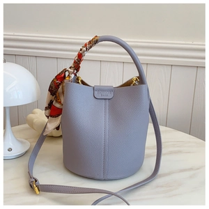 Detailed macro of lavender lychee grain leather bucket bag with silk scarf accessory