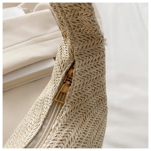Detailed macro view of high-quality golden metal zipper on beige woven straw handbag