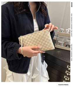 Macro shot of beige envelope clutch bag featuring classic M-pattern and metal zipper