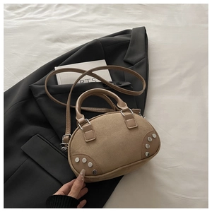 Close-up of khaki retro crossbody pillow bag with silver studs on a dark blazer background