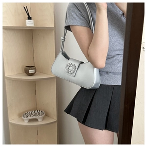 Silver baguette bag with a crystal buckle shown on shoulder for sizing reference
