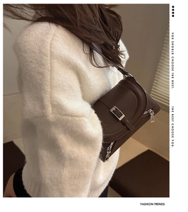 Close-up of dark brown leather shoulder bag with silver hardware and zipper detail