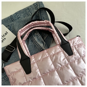 Close-up of pink quilted puffer tote with glossy finish, black handles and shoulder strap